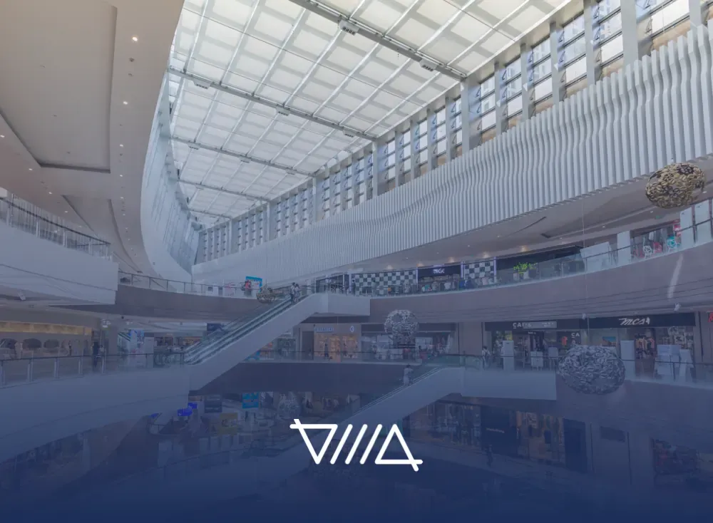 Interior de un centro comercial con escaleras eléctricas, balcones y techo de vidrio