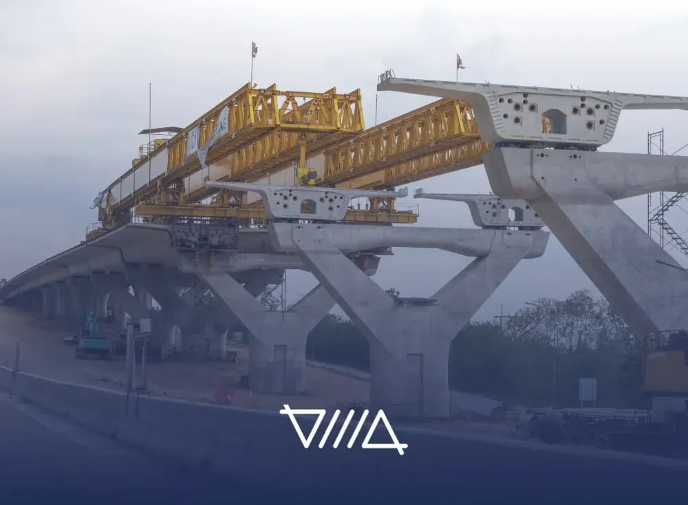 Puente de concreto en construcción con una estructura amarilla de montaje sobre una vía