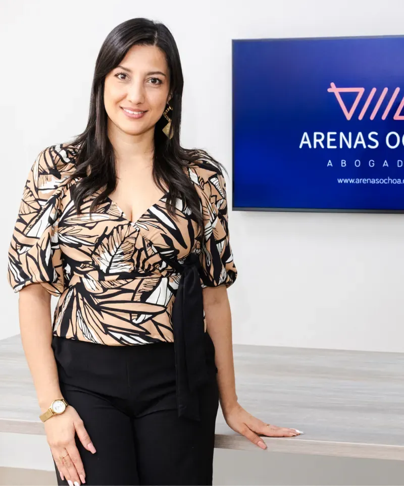 Claudia Carvajalino, gerente jurídica, junto a una pantalla con el logo de Arenas Ochoa