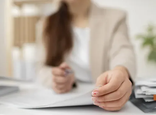 Mano de una mujer sobre hojas de un documento en un escritorio, redacción de contratos